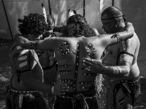 "Deaf in Dance" in yellow text next to a First Nations Australian person wearing a grass skirt in ceremonial body paint and holding clapsticks